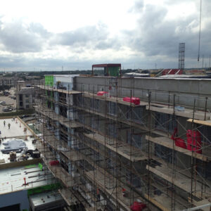 Construction site view with scaffolding, featuring a partially built multi-story building under a cloudy sky, illustrating the construction industry's dynamics relevant to fractional CMO services.