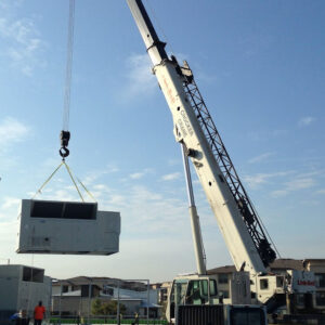 Crane lifting a large construction unit at a building site, highlighting construction logistics and equipment management.