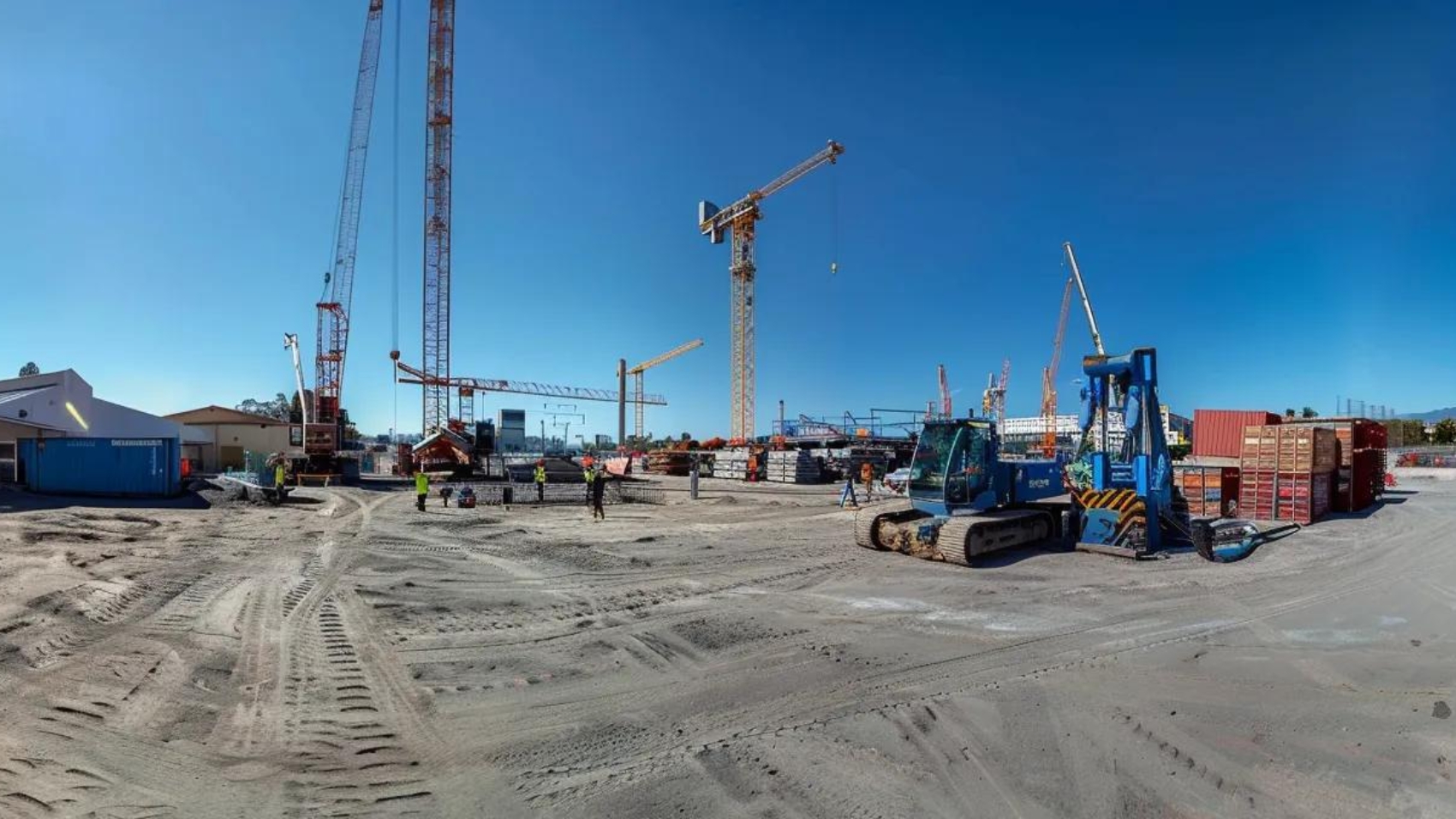 a construction site bustling with workers and machinery, surrounded by towering cranes under a clear blue sky.