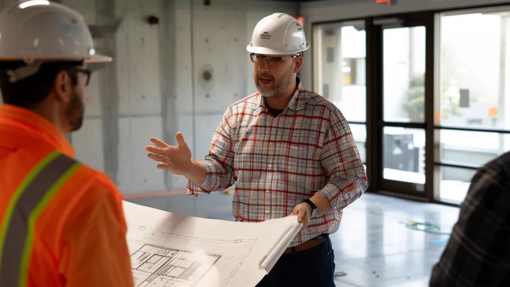 a construction marketing professional confidently presenting a blueprint to a group of interested potential clients at a sleek modern office.