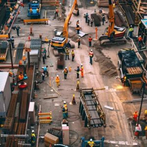 Aerial view of a busy construction site with workers, heavy machinery, and construction materials, illustrating effective project management and teamwork in the construction industry.