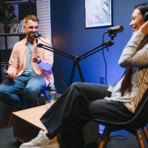 Podcast hosts engaging in conversation with microphones, set in a modern studio, relevant to architecture marketing discussions.