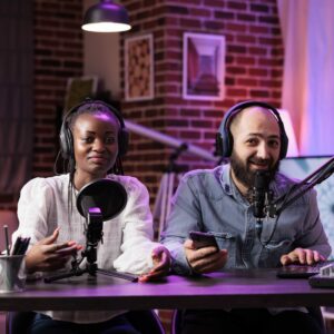 Two podcast hosts in a recording studio, engaging with microphones and discussing construction topics, with a modern backdrop.