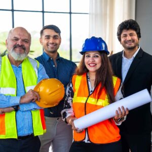 Group of diverse construction professionals in safety gear, including hard hats and reflective vests, holding blueprints, representing collaboration in the construction industry.
