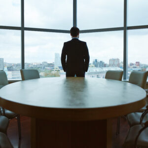 Business professional standing in front of large conference table, overlooking city skyline through floor-to-ceiling windows, symbolizing leadership and strategic decision-making in business development.